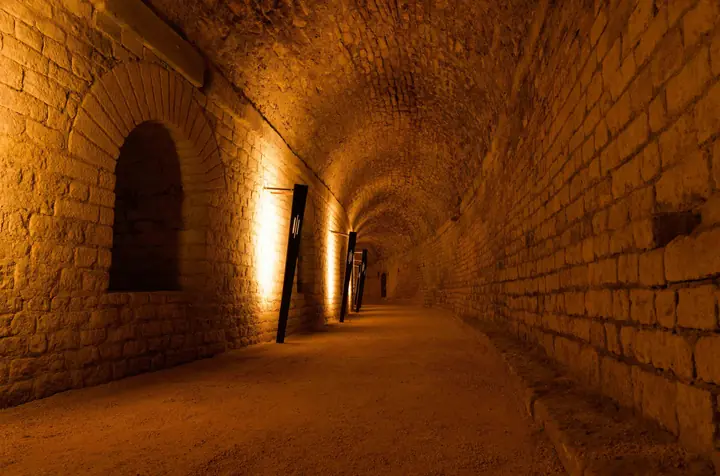 Galerie voûtée des souterrains de l'amphithéâtre d'Arles éclairée par des torches à LED