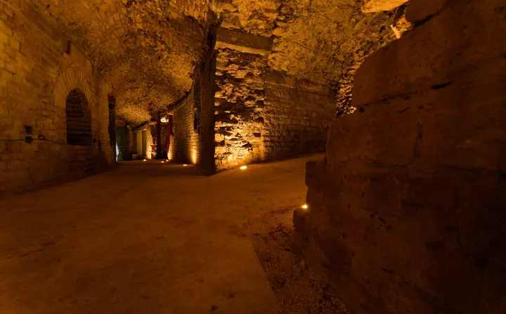 Souterrains de l'amphithéâtre d'Arles, lumière chaude des torches et des encastrés de sol